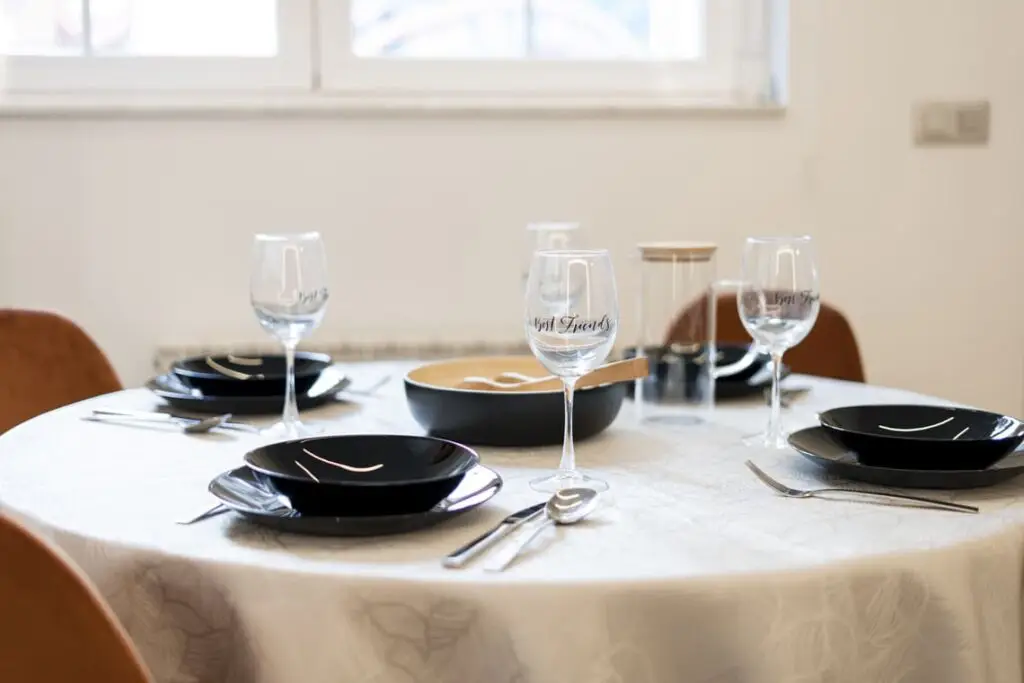 Vajilla con copas de vino y platos en una mesa de comedor.